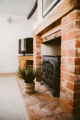 a brick fireplace in a living room with a plant at 1 Chantry Cottage in Tunstall