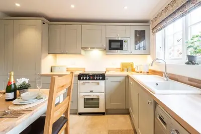 a kitchen with white cabinets and a sink and a stove at 1 Chantry Cottage in Tunstall