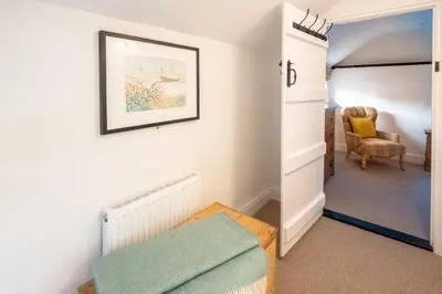 a room with a hallway with a bed and a chair at 1 Chantry Cottage in Tunstall