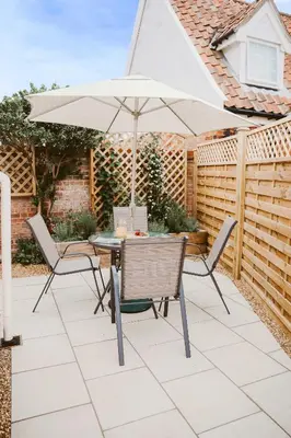 a table and chairs with an umbrella on a patio at 1 Chantry Cottage in Tunstall