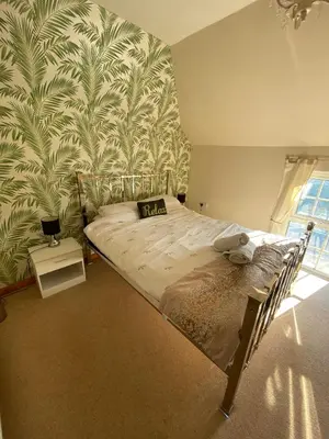 a bedroom with a large bed with a tropical wallpaper at Carlton Cottage Country Retreat - Perfect for Ipswich - Aldeburgh - Southwold - Thorpeness - Sizewell B - Sizewell C - Sleeps 13 in Little Glenham