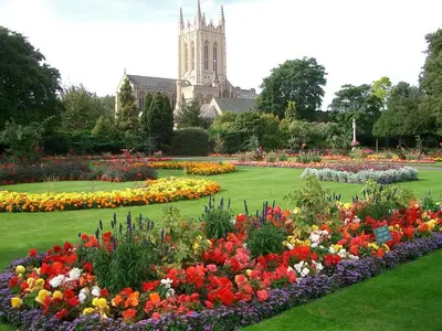 a garden with flowers in front of a church at The Annexe II in Mildenhall