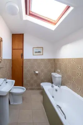 a bathroom with a tub and a toilet and a skylight at Sea Poppies in Thorpeness