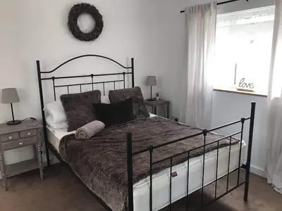 a bedroom with a bed with a black frame and a window at Stone Cottage in Nazeing