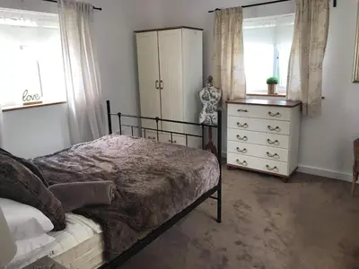 a bedroom with a bed and a dresser and windows at Stone Cottage in Nazeing