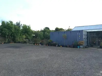 a gravel driveway with a blue building and plants at Stone Cottage in Nazeing