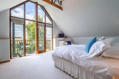 a bedroom with a bed and a large window at The Granary, Dunstall Green in Denham