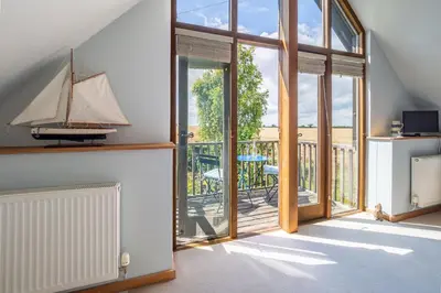 a living room with sliding glass doors and a sailboat on the wall at The Granary, Dunstall Green in Denham