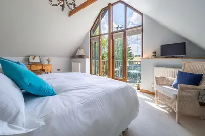 a bedroom with a large white bed and a window at The Granary, Dunstall Green in Denham
