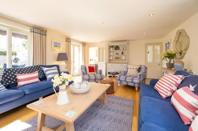 a living room with blue couches and a table at Winton Lodge in Aldeburgh