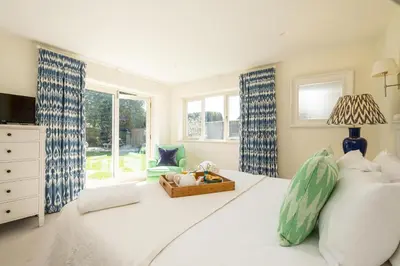 a bedroom with a large bed with a dresser and windows at Winton Lodge in Aldeburgh