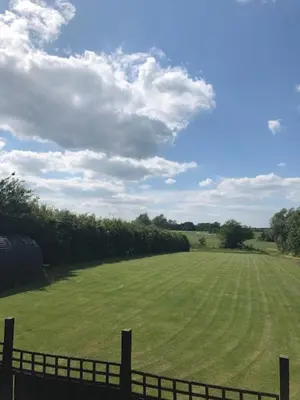 a large green field with a fence in the foreground at Rockinghams Farm in Layer Marney
