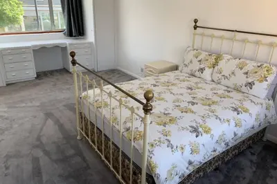 a bedroom with a bed with a floral bedspread at 5 Bedroom House with outdoor space in Upminster