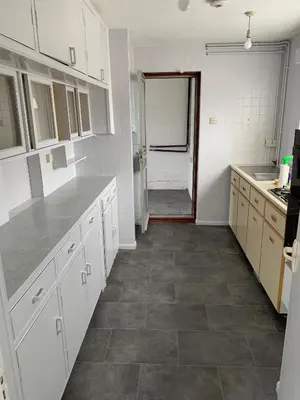 a kitchen with white cabinets and a tile floor at 5 Bedroom House with outdoor space in Upminster