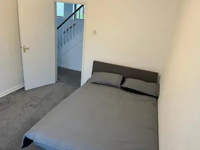 a bed in a white room with a staircase at 5 Bedroom House with outdoor space in Upminster