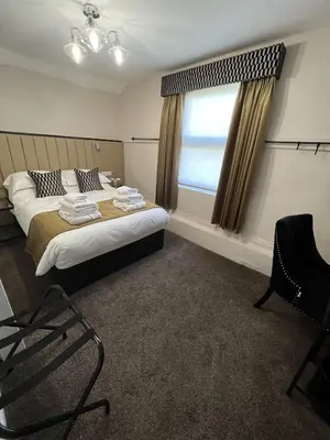 a bedroom with a bed and a window and a chair at The Kings Head in Chelmsford