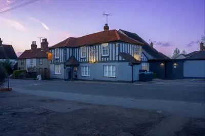 a white house with a red roof on a street at The Kings Head in Chelmsford