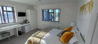 a bedroom with a bed and a desk and windows at Barn Farm Guest House in Cold Norton