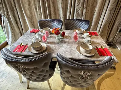 a dining room table with chairs and a table with flowers at Barnfields Retreat in Little Clacton