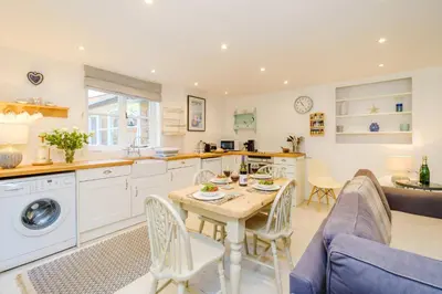 a kitchen and living room with a table and chairs at Theberton Cottage in Theberton