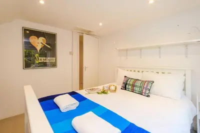 a bedroom with a large white bed with a blue blanket at Theberton Cottage in Theberton