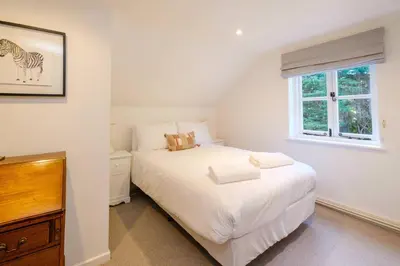 a bedroom with a white bed and a window at Theberton Cottage in Theberton
