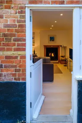 a door leading into a living room with a brick wall at Theberton Cottage in Theberton