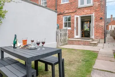 a picnic table with wine glasses on it in a yard at Longshore, Aldeburgh in Aldeburgh
