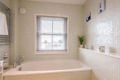 a white bathroom with a tub and a window at Longshore, Aldeburgh in Aldeburgh