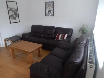 a living room with a black leather couch and a table at Science Park Suite in Cambridge