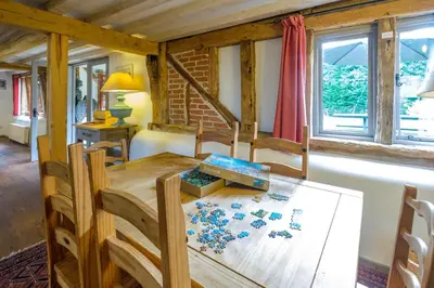 a dining room with a wooden table and windows at Old Hall Barn - Aldeburgh Coastal Cottages in Darsham