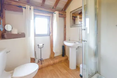 a bathroom with a toilet and a sink and a window at Old Hall Barn - Aldeburgh Coastal Cottages in Darsham