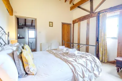 a bedroom with a large white bed and a window at Old Hall Barn - Aldeburgh Coastal Cottages in Darsham