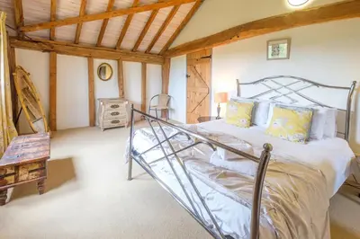 a bedroom with a bed and a wooden ceiling at Old Hall Barn - Aldeburgh Coastal Cottages in Darsham
