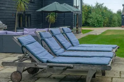 a couch with blue pillows sitting on a wooden cart at Old Hall Barn - Aldeburgh Coastal Cottages in Darsham