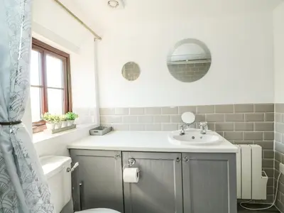 a bathroom with a sink and a toilet and a mirror at Chalk Cottage in Thetford