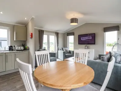 a kitchen and living room with a wooden table and chairs at Lodge 47 in Ipswich