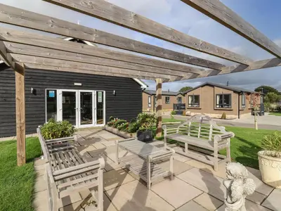 a patio with two benches and a wooden pergola at Lodge 47 in Ipswich