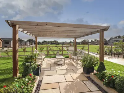 a wooden pergola with benches and flowers at Lodge 47 in Ipswich