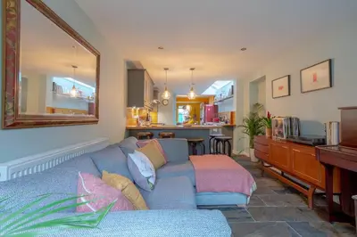 a living room with a blue couch and a kitchen at Lovely Central Cambridge Home in Cambridge