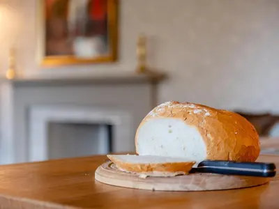 a loaf of bread on a cutting board with a knife at Little Crown in Winfarthing