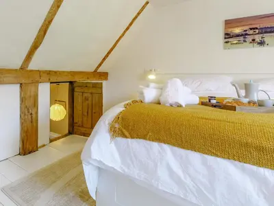 a bedroom with a large bed with white and gold sheets at Angel Lane in Woodbridge