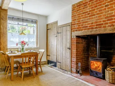 a dining room with a table and a brick fireplace at Angel Lane in Woodbridge