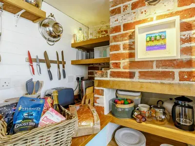 a kitchen with a brick wall and a counter with food at Angel Lane in Woodbridge