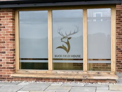 a window with a buck field house sign in it at Leveret Lodge in Burgh
