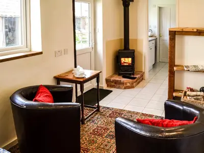 a living room with two chairs and a wood stove at The Bothy in Hockham