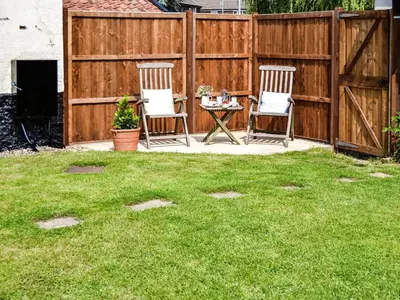 two chairs and a table in a yard with a fence at The Bothy in Hockham