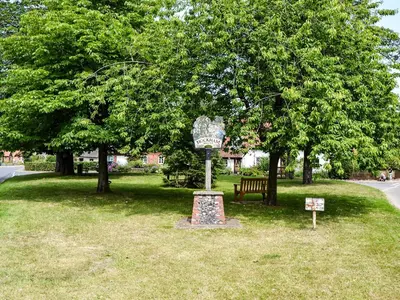 a park with a bench and a sign in the grass at The Bothy in Hockham