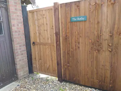 a wooden fence with a gate with a sign on it at The Bothy in Hockham
