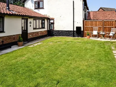 a yard with green grass in front of a house at The Bothy in Hockham